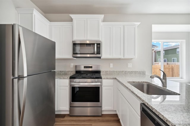 kitchen with sink, light stone counters, appliances with stainless steel finishes, dark hardwood / wood-style flooring, and white cabinetry