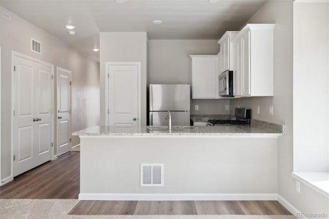 kitchen featuring kitchen peninsula, appliances with stainless steel finishes, light stone counters, sink, and white cabinetry