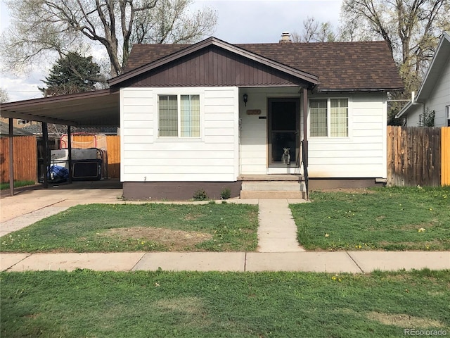 view of front of house featuring roof with shingles, a carport, and driveway