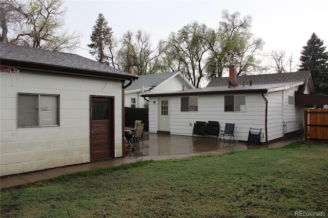 rear view of house featuring a patio, a shingled roof, and a chimney