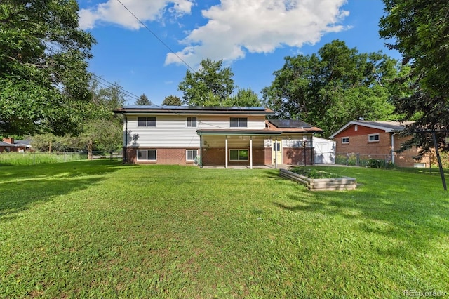 5193 Zinnia St, Arvada, CO 80002 - rear view of house with roof mounted solar panels, a patio, a fenced backyard, a garden, and brick siding