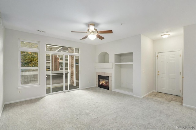 unfurnished living room with ceiling fan, light carpet, and a tile fireplace