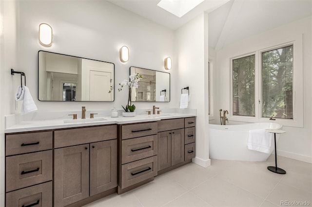 5401 E Dakota Ave Unit 22, Denver, CO 80246 - bathroom featuring lofted ceiling, double vanity, a skylight, a freestanding bath, and tile patterned flooring