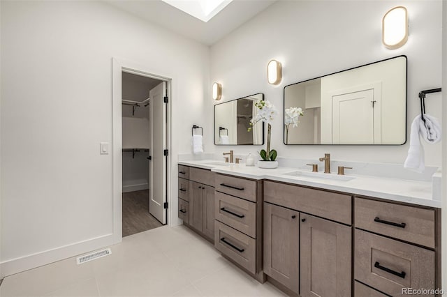 5401 E Dakota Ave Unit 22, Denver, CO 80246 - bathroom featuring double vanity, tile patterned floors, a walk in closet, and a skylight