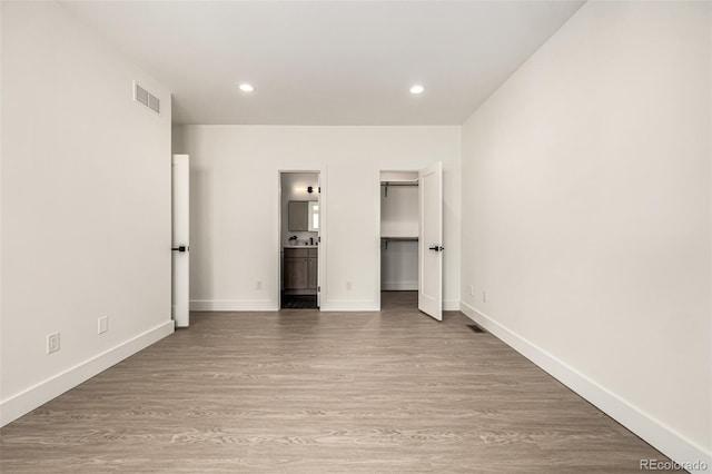 5401 E Dakota Ave Unit 22, Denver, CO 80246 - unfurnished bedroom featuring ensuite bathroom, recessed lighting, wood finished floors, and a walk in closet