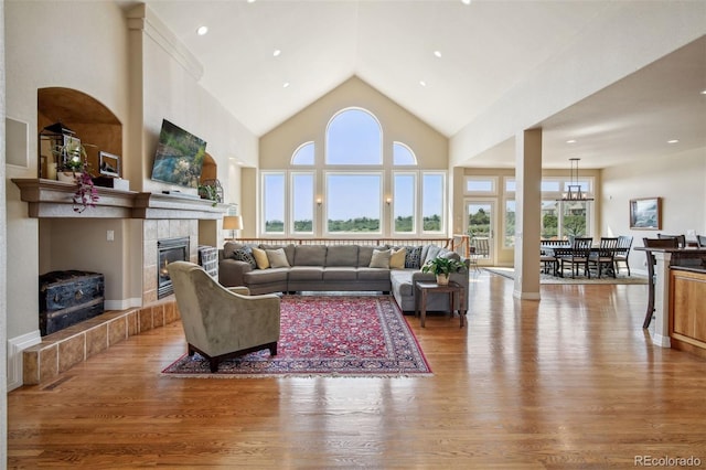 living room featuring a tiled fireplace, hardwood / wood-style floors, and high vaulted ceiling