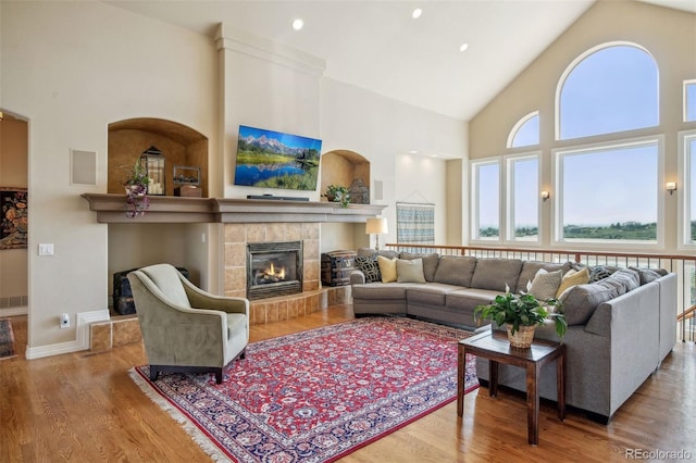 living room with hardwood / wood-style floors, high vaulted ceiling, and a fireplace