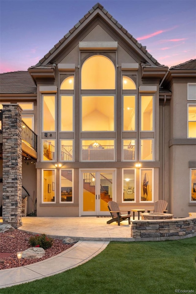 back house at dusk with a yard and a patio