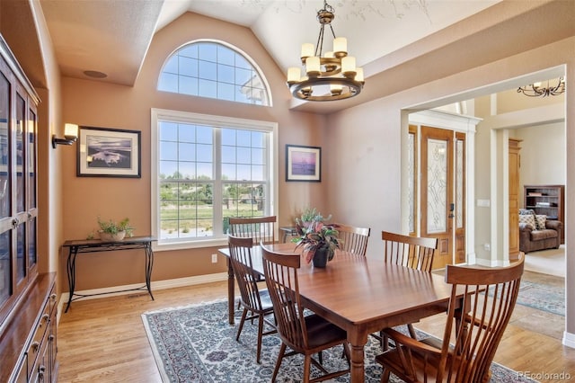 dining room featuring lofted ceiling, light hardwood / wood-style flooring, and an inviting chandelier