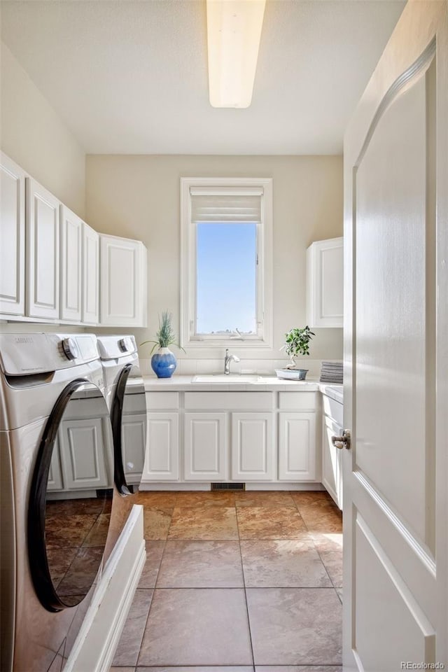 laundry area with cabinets, washing machine and dryer, and sink