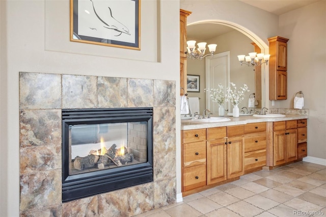 bathroom featuring vanity, a multi sided fireplace, an inviting chandelier, and tile patterned flooring