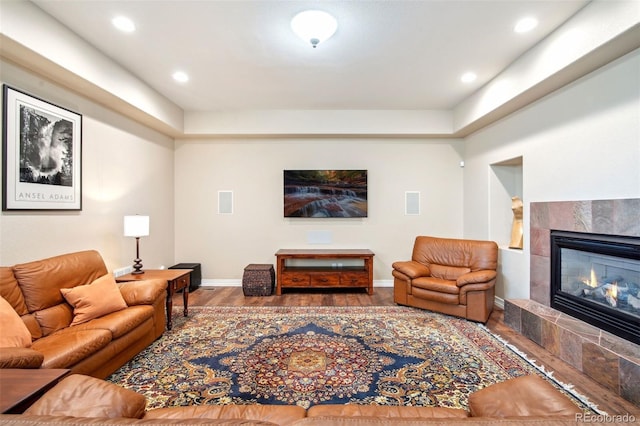 living room featuring a tiled fireplace and hardwood / wood-style flooring