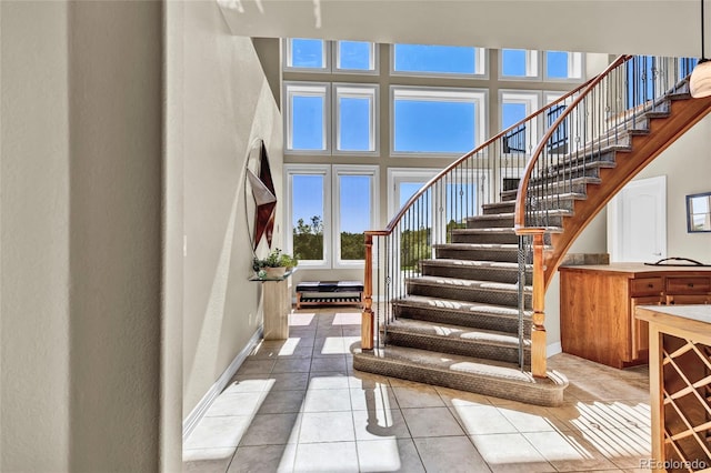 staircase featuring a towering ceiling and tile patterned floors