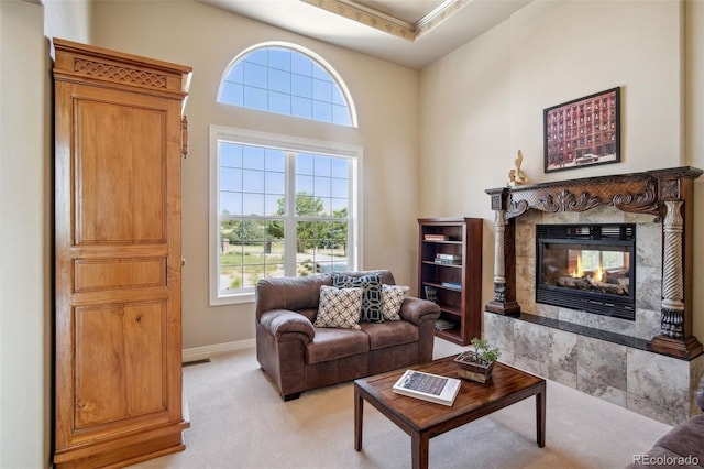 carpeted living room with a towering ceiling and a tile fireplace