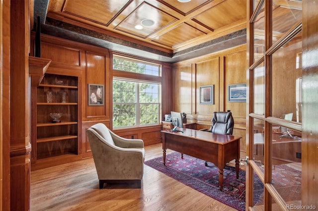 office space with wood-type flooring, ornamental molding, wooden walls, and coffered ceiling