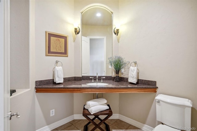 bathroom with toilet, sink, and tile patterned floors