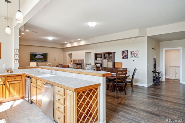 kitchen featuring hardwood / wood-style floors, beverage cooler, kitchen peninsula, sink, and hanging light fixtures