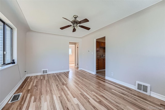 unfurnished room featuring ceiling fan, plenty of natural light, and light wood-type flooring