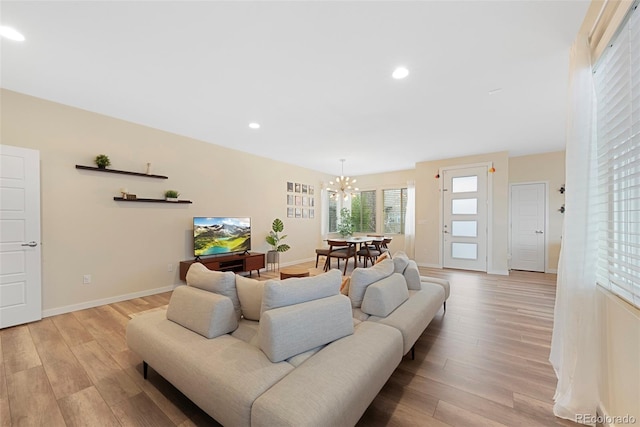 living area with light wood-type flooring, recessed lighting, baseboards, and a notable chandelier