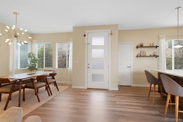 dining space featuring baseboards, a chandelier, and light wood-style flooring