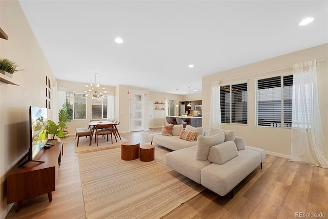 living room with light wood-style floors, recessed lighting, baseboards, and a notable chandelier