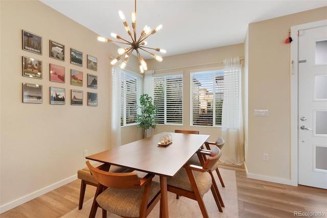 dining room featuring baseboards, light wood-type flooring, and a notable chandelier