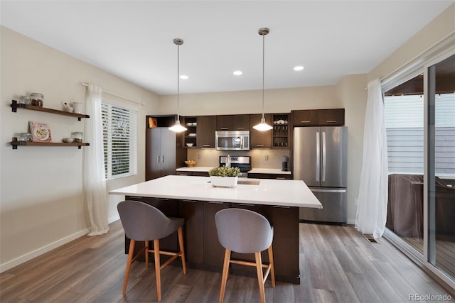 kitchen with open shelves, wood finished floors, dark brown cabinetry, light countertops, and stainless steel appliances