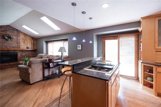 17530 E Caspian Pl, Aurora, CO 80013 - kitchen featuring light wood finished floors, stainless steel gas cooktop, lofted ceiling, a breakfast bar area, and a fireplace
