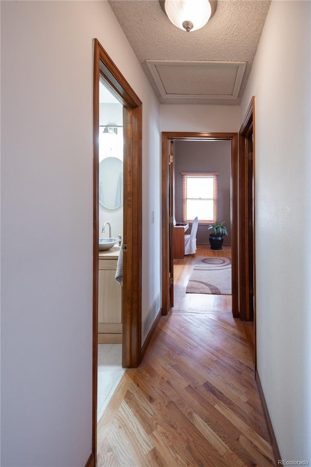 17530 E Caspian Pl, Aurora, CO 80013 - hall with light wood-style flooring, attic access, and a textured ceiling