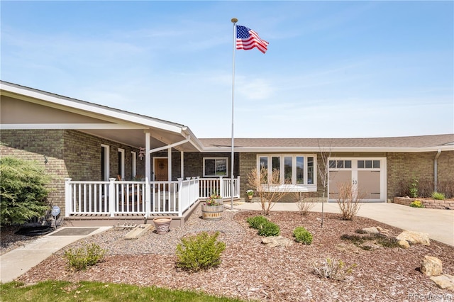 ranch-style home featuring a porch, brick siding, concrete driveway, an attached garage, and a shingled roof