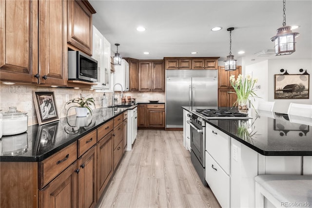 kitchen featuring pendant lighting, high quality appliances, a center island, a sink, and light wood-style flooring