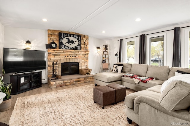 living room with a stone fireplace, recessed lighting, wood finished floors, and a baseboard heating unit
