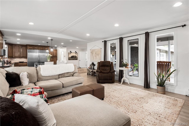 living room with recessed lighting, light wood-style floors, and vaulted ceiling