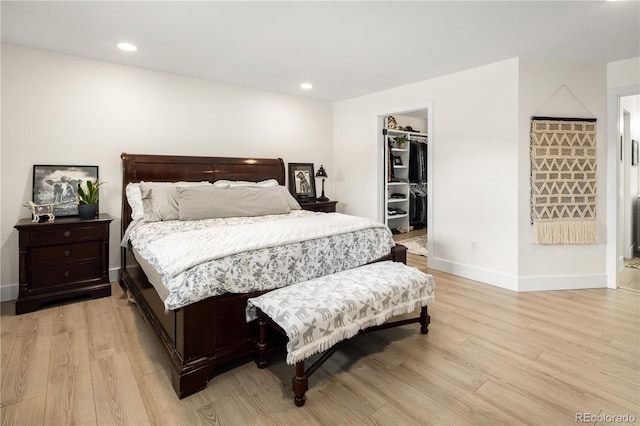 bedroom featuring recessed lighting, baseboards, light wood-type flooring, and a spacious closet