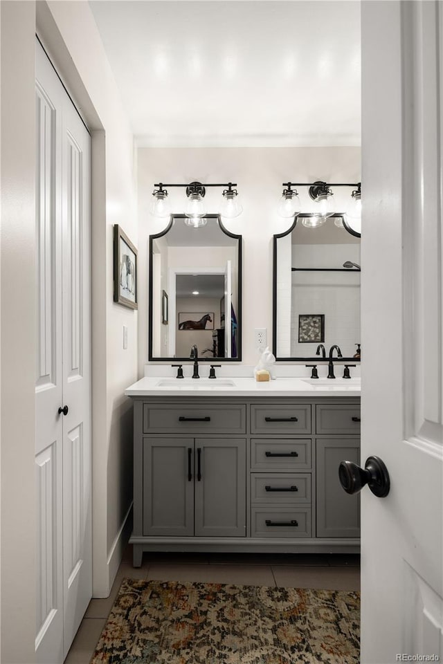 full bath with double vanity, a sink, and tile patterned floors