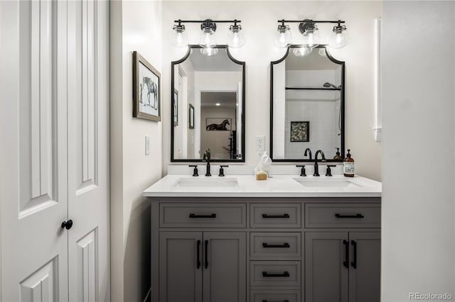 bathroom with double vanity, a sink, and a tile shower