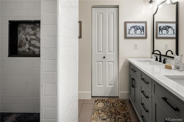 bathroom featuring double vanity, a sink, baseboards, and tile patterned flooring