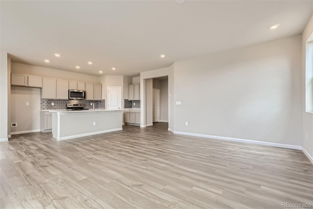 kitchen featuring light hardwood / wood-style floors, sink, an island with sink, stainless steel appliances, and backsplash