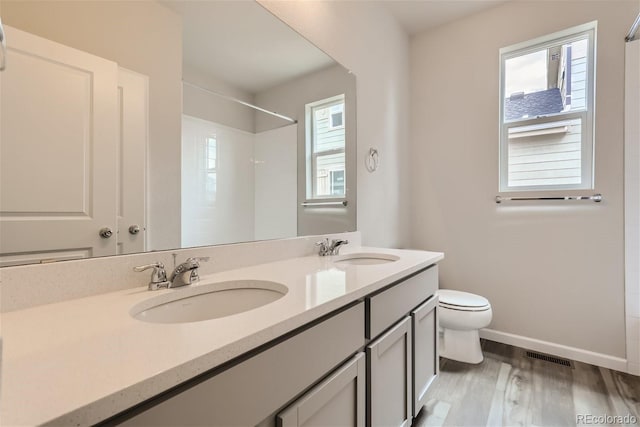 bathroom featuring walk in shower, wood-type flooring, vanity, and toilet