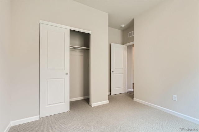 unfurnished bedroom with light carpet and a closet