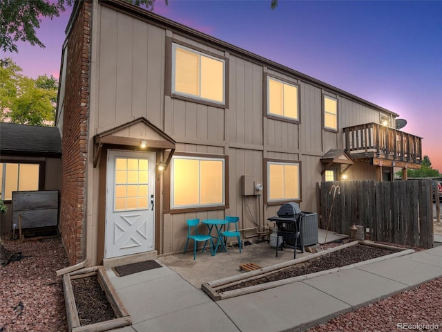 back house at dusk with a patio and a balcony