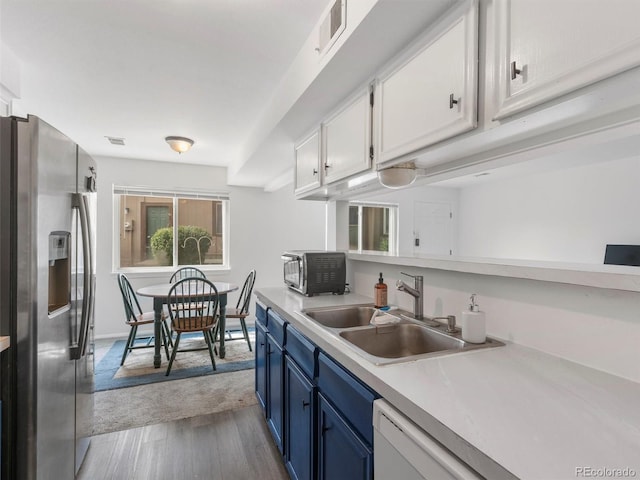 kitchen featuring white cabinetry, sink, stainless steel fridge, white dishwasher, and blue cabinetry