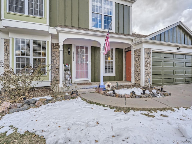 snow covered property entrance with a garage