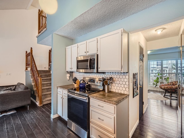 kitchen with backsplash, a textured ceiling, stainless steel appliances, white cabinets, and dark hardwood / wood-style floors