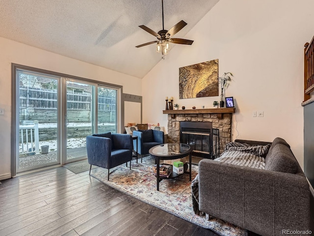 living room featuring a textured ceiling, ceiling fan, hardwood / wood-style flooring, high vaulted ceiling, and a stone fireplace