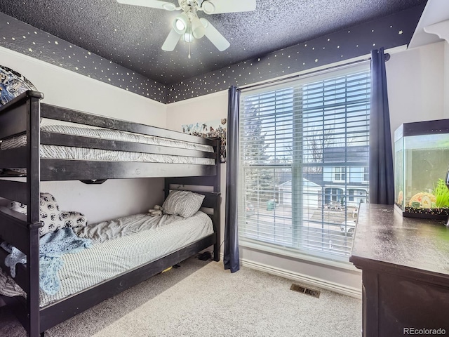 bedroom with ceiling fan, carpet floors, and a textured ceiling