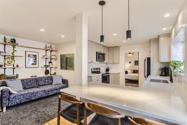 kitchen featuring a kitchen breakfast bar, decorative light fixtures, sink, and appliances with stainless steel finishes