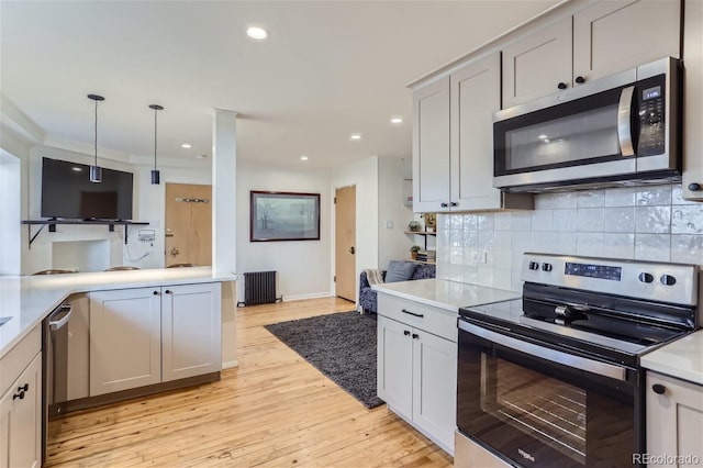 kitchen with hanging light fixtures, decorative backsplash, light wood-type flooring, radiator heating unit, and stainless steel appliances