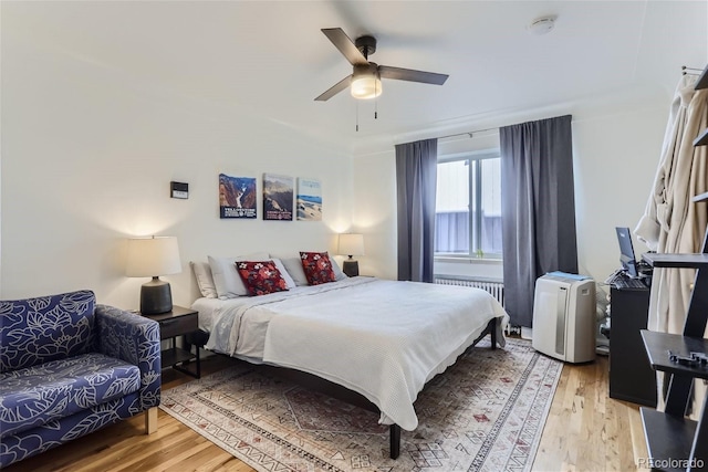 bedroom featuring ceiling fan, light hardwood / wood-style floors, and radiator heating unit