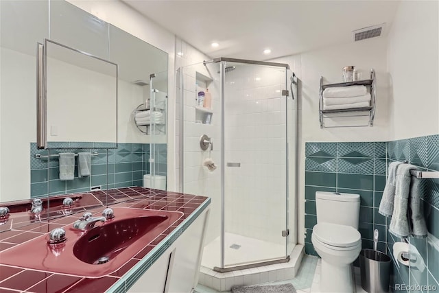 bathroom featuring tile patterned flooring, a shower with shower door, and tile walls